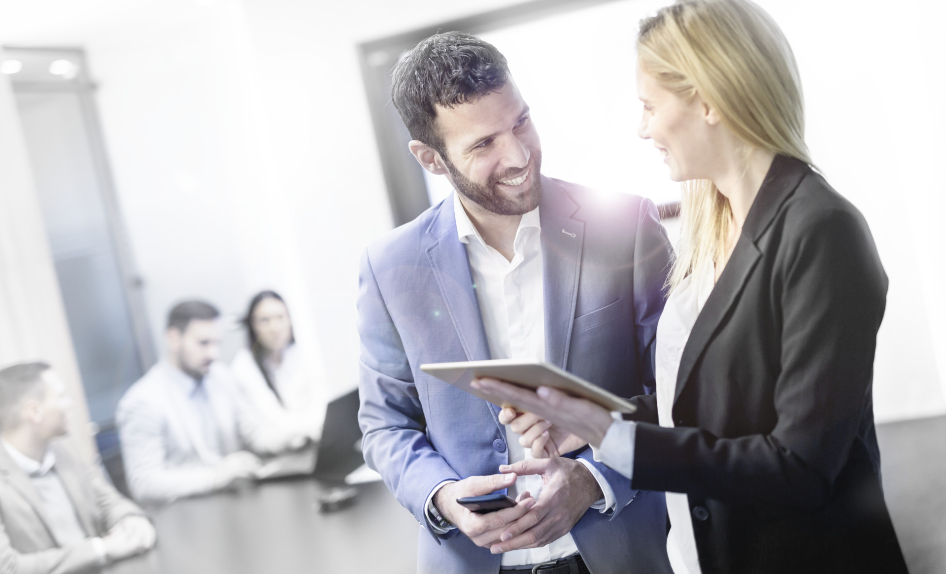 Man and woman are discussing in an office with people sitting on a desk