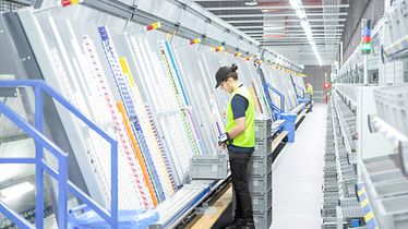 Warehouse worker filling A-frame equipment with stock from stock totes