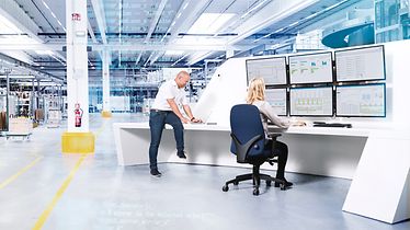 Man en vrouw werken met grote computerschermen aan logistieke software in een magazijn