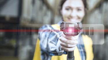 Vrouw houdt scanapparaat in haar hand en scant een barcode van een product