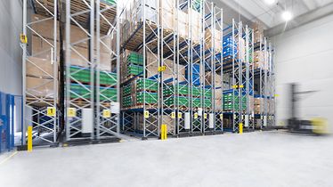 Hoge schappen gevuld met pallets en dozen in een magazijn