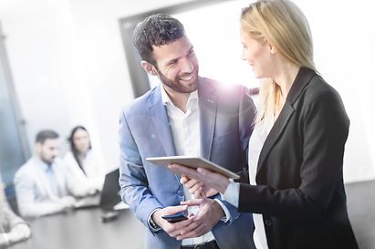 Man and woman are discussing in an office with people sitting on a desk