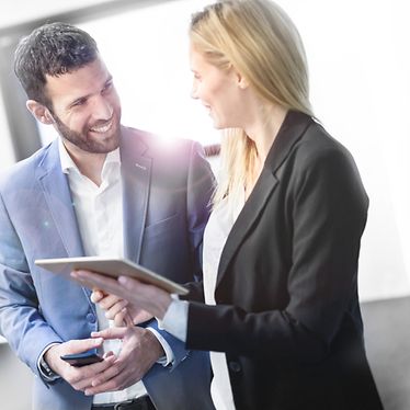 Man and woman are discussing in an office with people sitting on a desk