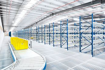 SSI Schaefer empty shelving with conveyor and yellow totes