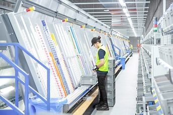 Warehouse worker filling A-frame equipment with stock from stock totes