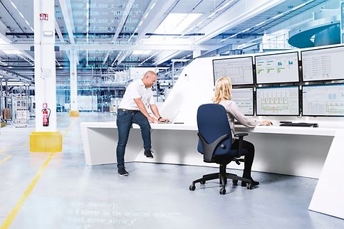 Man en vrouw werken met grote computerschermen aan logistieke software in een magazijn