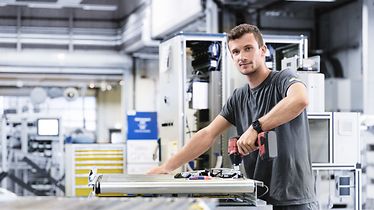 HR_young man works in the production, holds a drill in his hands